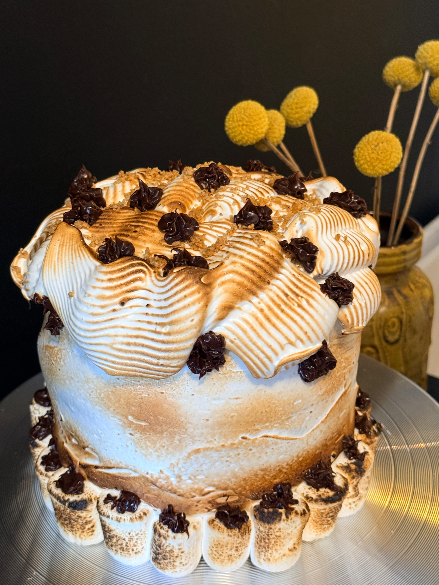 A toasted meringue cake with torched swirls, chocolate rosettes and graham crumble